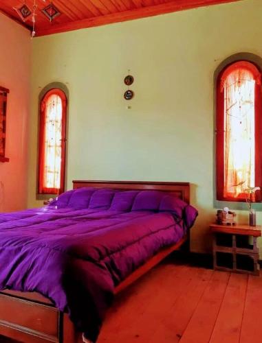 a purple bed in a bedroom with two windows at Espacio Kaskai in San Marcos Sierras
