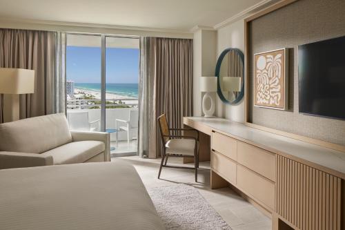a hotel room with a bed and a desk and a television at Loews Miami Beach Hotel in Miami Beach