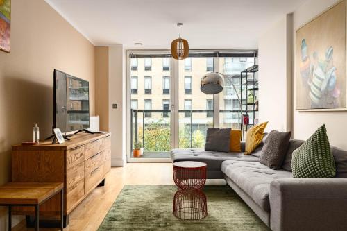 a living room with a couch and a large window at Stylish Greenwich Apartment with Balcony And River Views in London