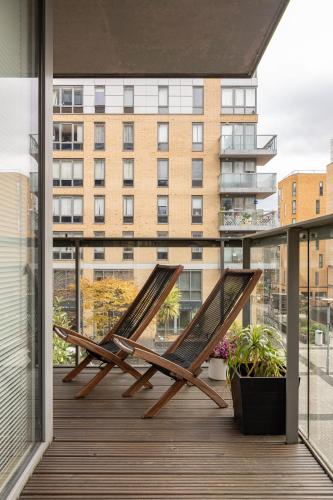 two chairs on a balcony with a view of a building at Stylish Greenwich Apartment with Balcony And River Views in London