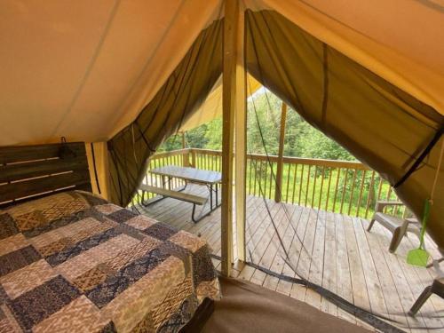 a tent with a bed and a wooden deck at Beautiful Tented Cabin Nestled Amidst Trees with Incredible Hiking Trails Near in Logan, Ohio in Logan