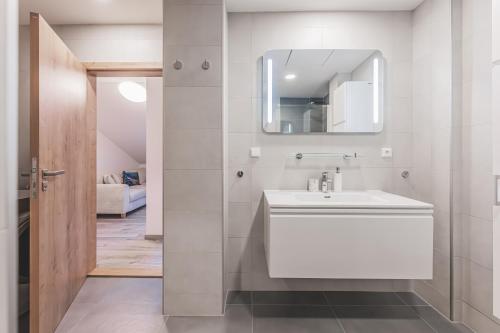 a bathroom with a white sink and a mirror at Moderní podkrovní byt 2KK u náměstí s klimatizací in Hradec Králové
