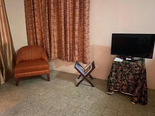 a living room with a chair and a television at charming 1 bedroom house in Port-of-Spain