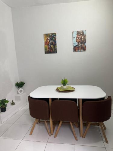 a dining room table and chairs with paintings on the wall at T2 Vacation in Mindelo in Mindelo