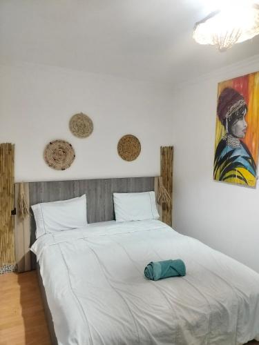 a bedroom with a large white bed and a painting at Akwaba lodge in Salé