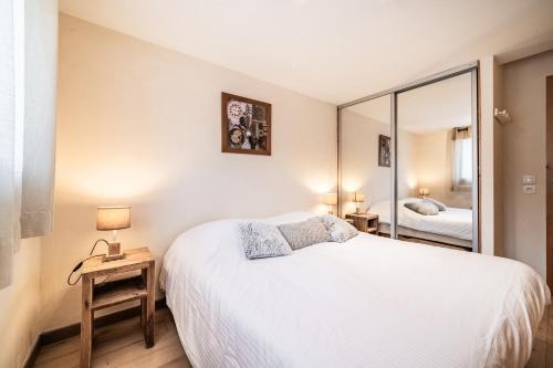 une chambre avec un grand lit blanc et un miroir dans l'établissement Le Cristal 2, aux Gets