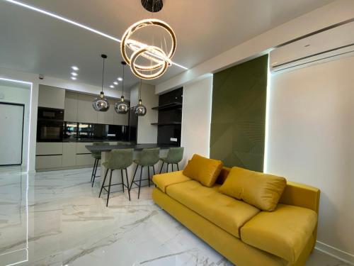 Oasis في كيشيناو: غرفة معيشة بها أريكة صفراء ومطبخ