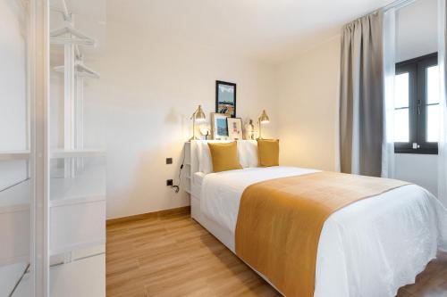 ein weißes Schlafzimmer mit einem großen Bett und gelben Kissen in der Unterkunft Esencia House Bajo las Estrellas in Llanos de la Concepción