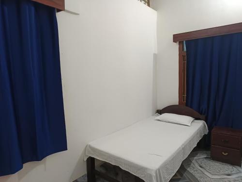 a small room with a bed and a blue curtain at Shahi House in Bodh Gaya
