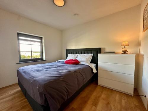 a bedroom with a bed with a dresser and a window at Petit Wilogne in Dinez