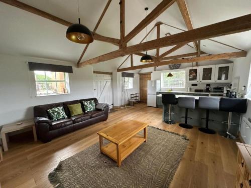 una sala de estar con un sofá y una mesa en Tranquil detached barn in Sherborne St John, en Sherborne Saint John