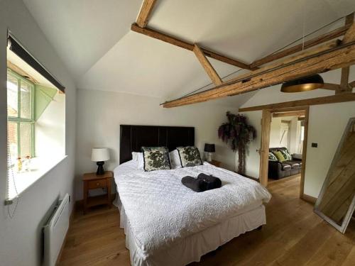 1 dormitorio con 1 cama con sábanas blancas y suelo de madera en Tranquil detached barn in Sherborne St John, en Sherborne Saint John