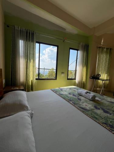 古瓦哈提Hemalata Hilltop Residency Kamakhya的卧室设有一张大床,设有两个窗户