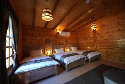 a bedroom with three beds in a log cabin at Aviary AlUla 3 in Al-ʿUla