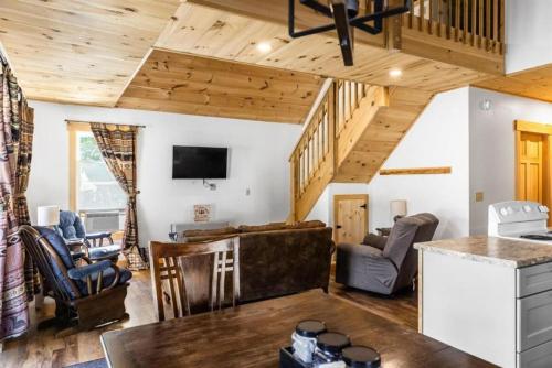 a kitchen and living room with wooden ceilings at Cozy Secluded Cabin with Fire Pit and Barbecue in Greenville, Maine in Greenville