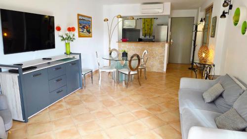 ein Wohnzimmer mit einer Couch, einem Fernseher und einem Tisch in der Unterkunft Les Soleiades in La Londe-les-Maures