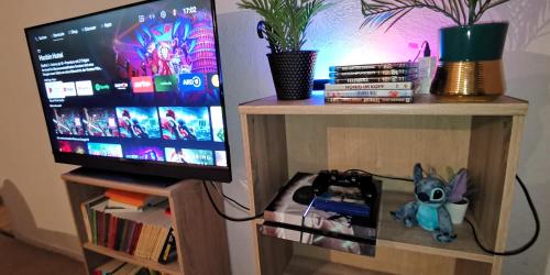 a tv on a wooden stand with a shelf with books at Ganzes Ferienhaus in Kassel mit umzäunten 1000qm Garten, Komfort Küche, Bad, Wohnzimmer, 4 Schlafzimmer, 8 Betten, Gratis Parkplätze, BBQ Pavillion, so privat wie zu Hause in Kassel