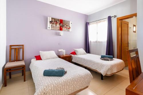 Una pequeña habitación con dos camas y una silla. en 3 bedroom villa with pool and jacuzzi, en Playa Blanca