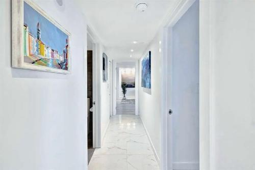 a hallway with white walls and paintings on the walls at Luxurious Three-Bedroom Oceanfront Apartment with Private Balcony in Hollywood Beach