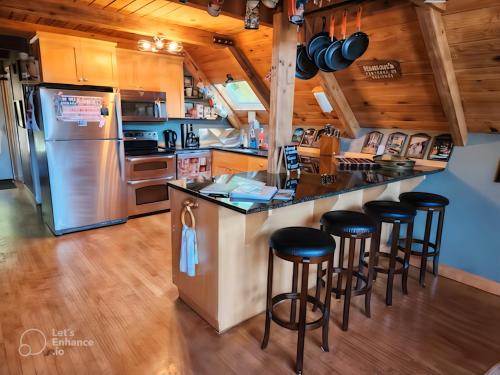 奥克港Room in Shared A-Frame Chalet的厨房配有冰箱和带凳子的酒吧