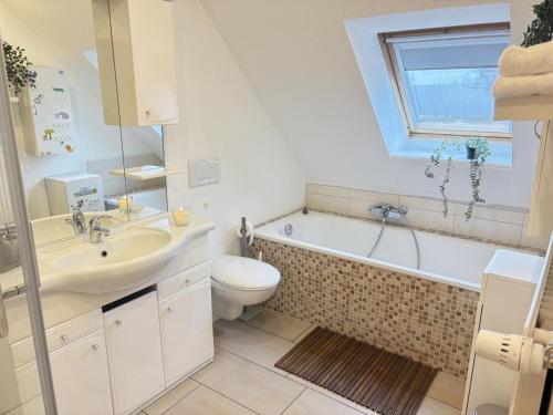 a bathroom with a sink and a tub and a toilet at Elkjer 24 in Großenwiehe