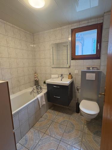 a bathroom with a tub and a toilet and a sink at Gîte au cœur du vignoble in Riquewihr