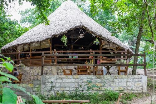 a hut with a thatched roof and a stone wall at Casa Lorette in Martínez