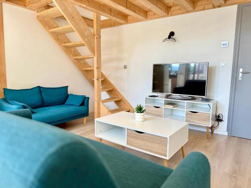 a living room with a blue couch and a tv at Le Bernascon - Mezzanine et Calme in Aix-les-Bains