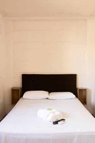 a white bed with a black headboard and a towel on it at Hospedagem Quinta do Correia in Penha