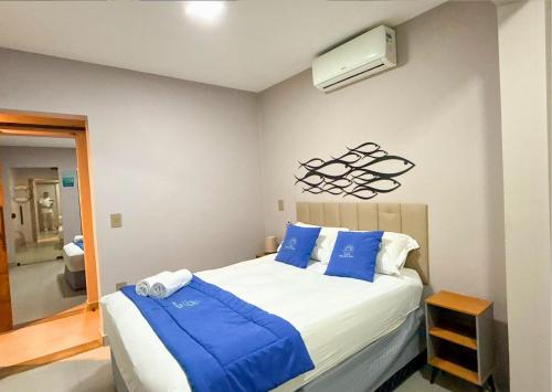 a bedroom with a large bed with blue pillows at Luxo Frente Mar em 7 Qtos com Ar sendo 4 suites para até 18 pessoas, 2 Jacuzzi Aquecidas, piscina, brinquedoteca, 5min de Castelhanos in Anchieta