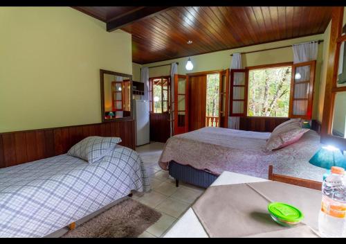 モンテ・ヴェルデにあるChalés Caminho das Pedrasのベッド2台とテーブルが置かれた寝室