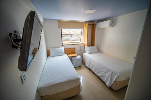 a small room with two beds and a flat screen tv at Amazinn Hotel in Belém