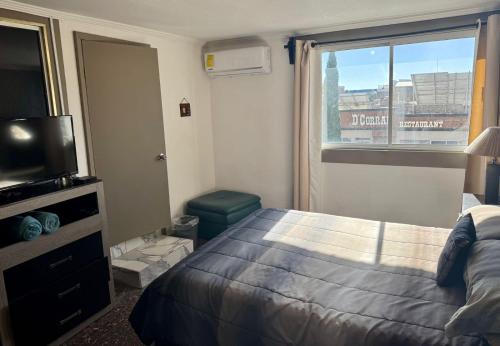 ein Schlafzimmer mit einem Bett und einem Fernseher und einem Fenster in der Unterkunft Suite 3 del Centro de Cuauhtémoc Chihuahua in Cuauhtémoc