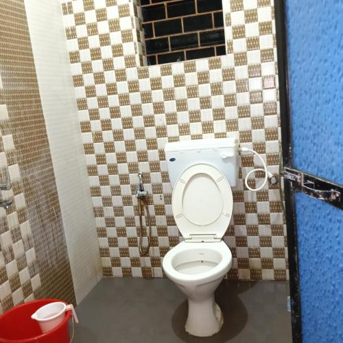a bathroom with a toilet with a tiled wall at One love guest house morjim in Arambol