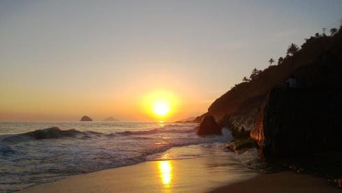a sunset on a beach with the ocean at Pousada DiMari in Boicucanga
