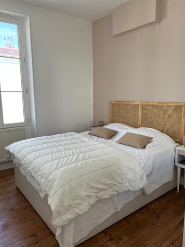 een slaapkamer met een groot bed met witte lakens en een raam bij Location Ile d'Oléron, plage et commerces à pieds in Le Château-dʼOléron