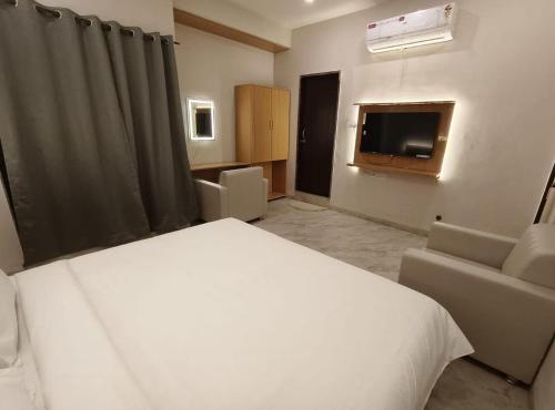 a bedroom with a bed and a couch and a television at Vilaasitaa Family Suites in Indore