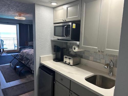 a kitchen with a sink and a bedroom with a bed at Daytona Inn in Daytona Beach