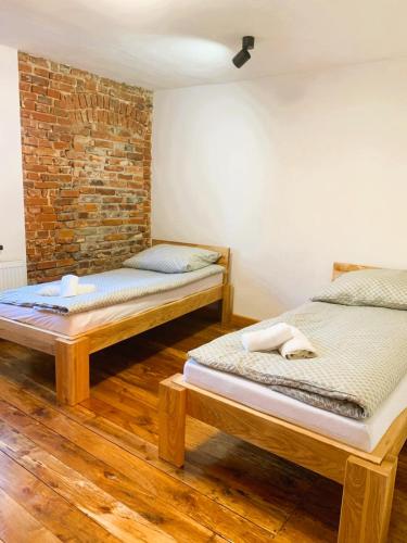 twee bedden in een kamer met een bakstenen muur bij Skansen- Bożejów in Radomierowice