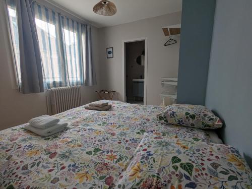 le logis d'Héloïse في بواتييه: غرفة نوم بها سرير مزين بغطاء سرير مزهر ووسائد