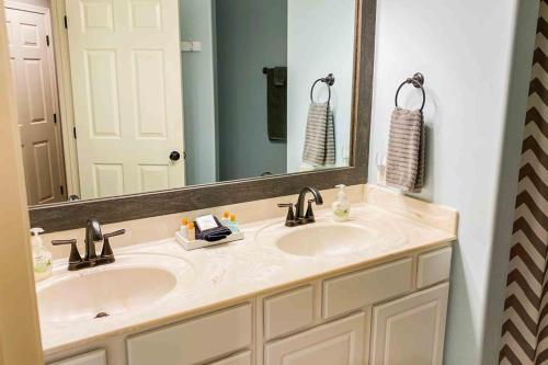 Un baño con dos lavabos y un espejo grande. en The Calm at Emerald Bay, en Lake Ozark