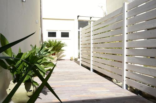 een houten looppad met planten en een wit hek bij S'Apposentu 15 in Monserrato