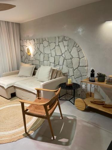 a living room with a white couch and a stone wall at Diamantino Residence 27 -Refúgio, luxo e conforto em Mucugê in Mucugê