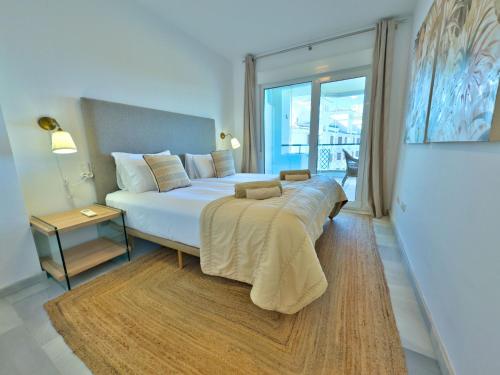 a bedroom with a bed with a table and a window at Apartamento en primera línea de playa, Mi Capricho in Sitio de Calahonda