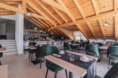 a restaurant with wooden ceilings and tables and green chairs at Galega Villas in Milharado