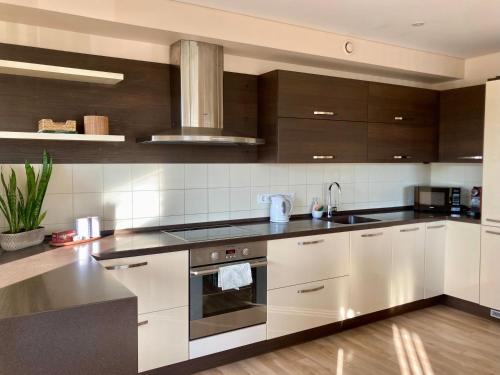 a kitchen with white cabinets and a stove top oven at Sunny Lotus Apartamentai in Druskininkai