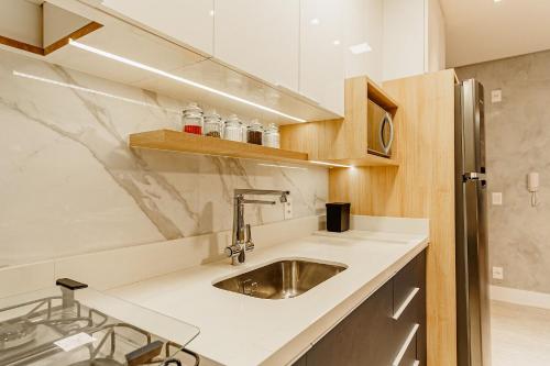 a kitchen with a sink and a stainless steel refrigerator at Elyseés Residencial Flipchave ELY000 in Joinville