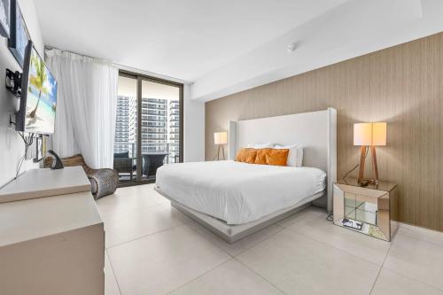a bedroom with a white bed and a large window at Oceanfront Lyfe Resort in Hollywood