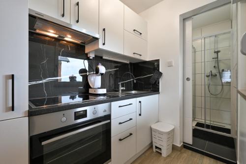 a kitchen with white cabinets and black counter tops at View&Wine Jacuzzi -Tuheljske toplice in Veliko Trgovišće