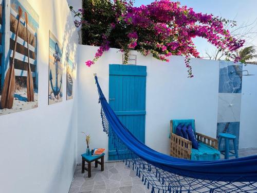 um quarto com uma rede azul e flores na parede em Casa Grécia Jericoacoara em Jericoacoara
